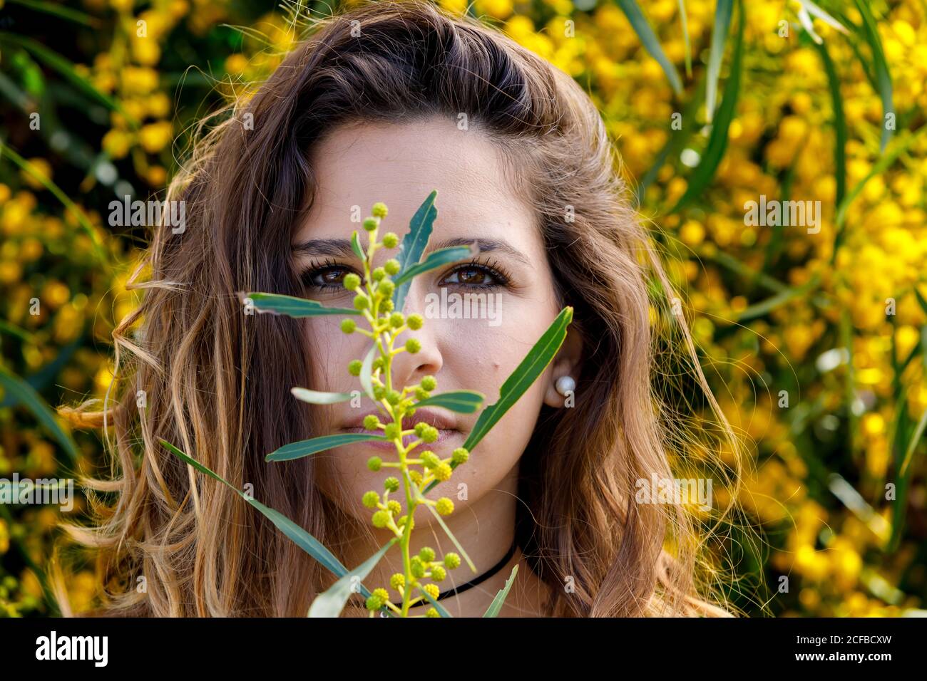 Junge Frau riecht Blume aus Gartenbusch Stockfoto
