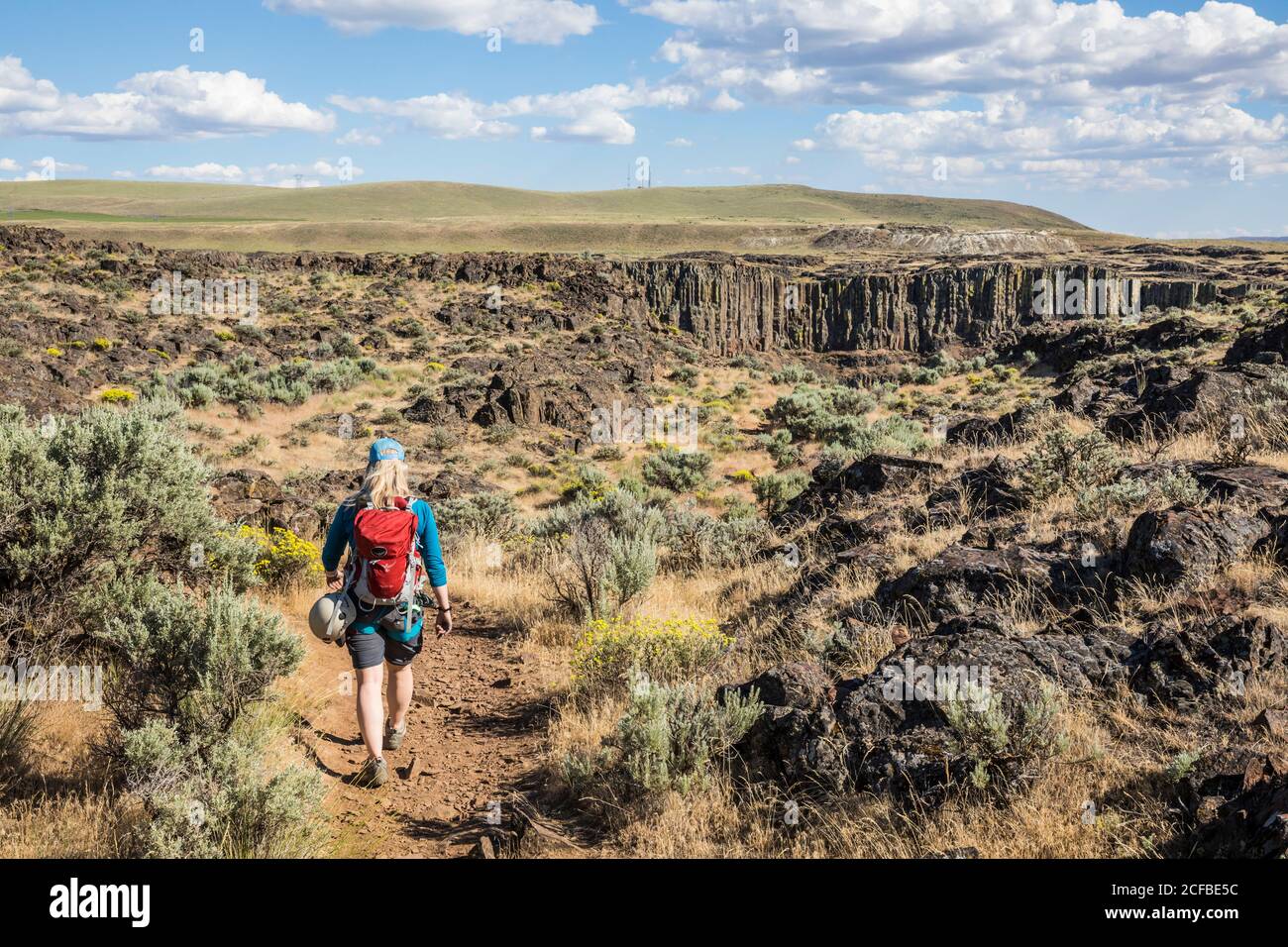 Eine Frau, die auf einem Wanderweg mit einem Klettersteig unterwegs ist Harness und Tragen eines Rucksacks in der Nähe der Franzosen Coulee auf den Weg Echo Basin in Eastern Washingto Stockfoto