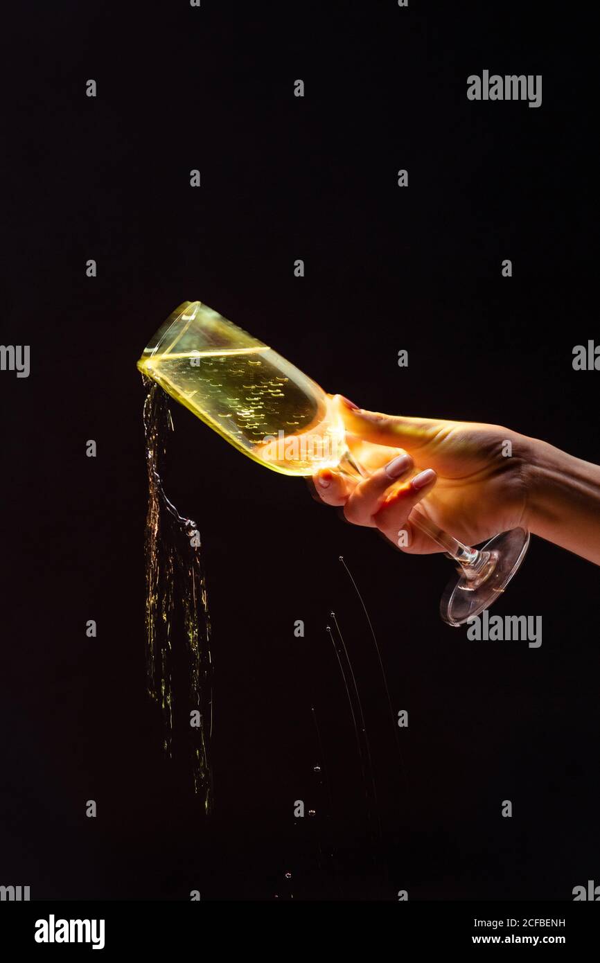 Anonymous Crop Person Gießen Alkohol aus Glas während der Party auf Schwarzer Hintergrund Stockfoto