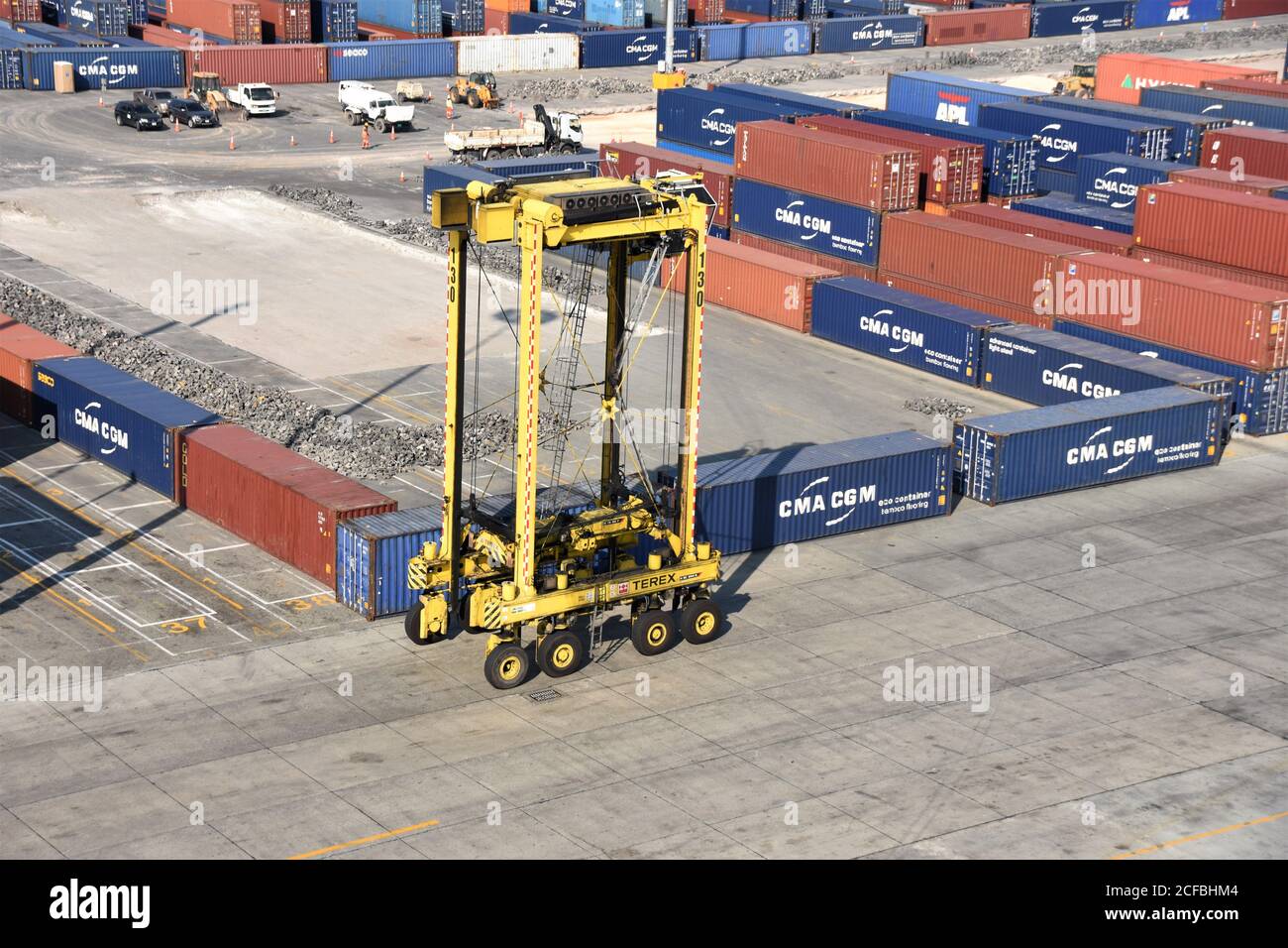 Ein Straddle Carrier im Kingston Freeport Terminal, der in der Nähe von Containern vorbeifährt. Der gelbe Sattelzug ist leer und bewegt sich zum Verladen in Richtung Schiffe. Stockfoto