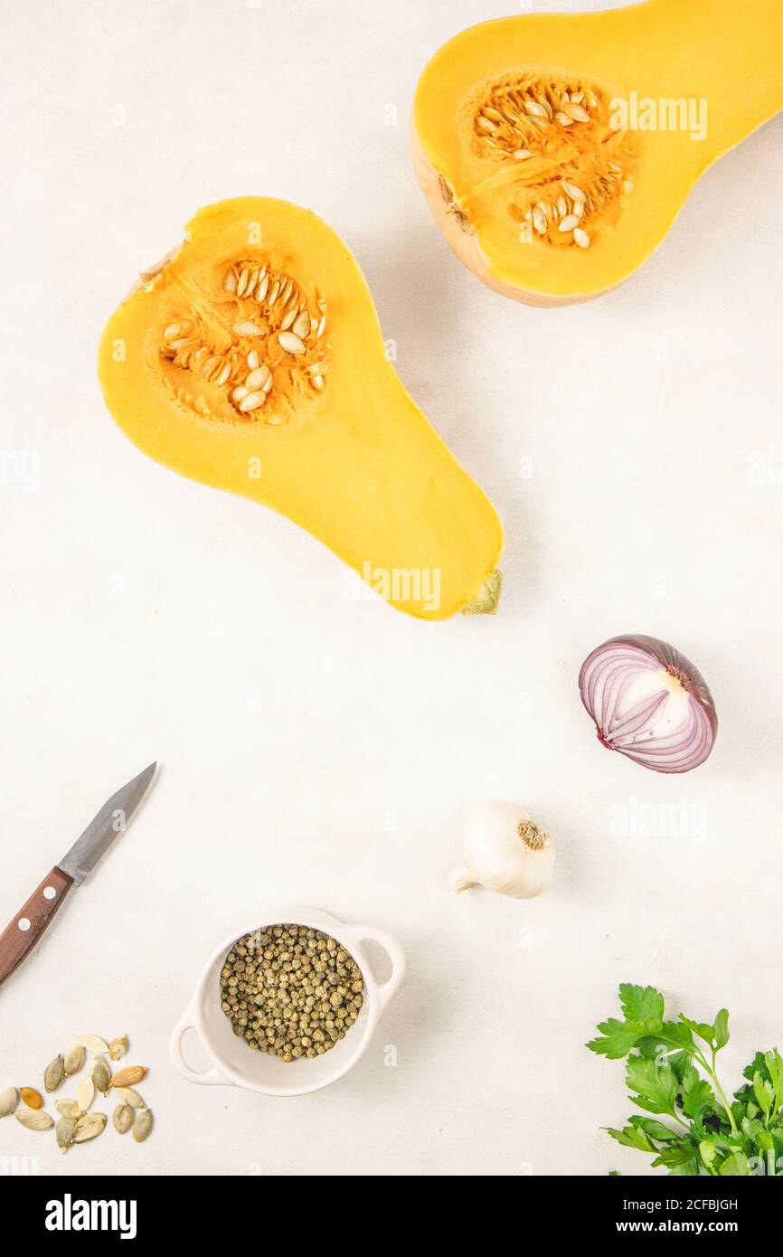 Hälften von rohem Bio-Butternusskürbis mit Gewürzen und Zutaten. Frischer Kürbis. Draufsicht, flach liegend. Stockfoto