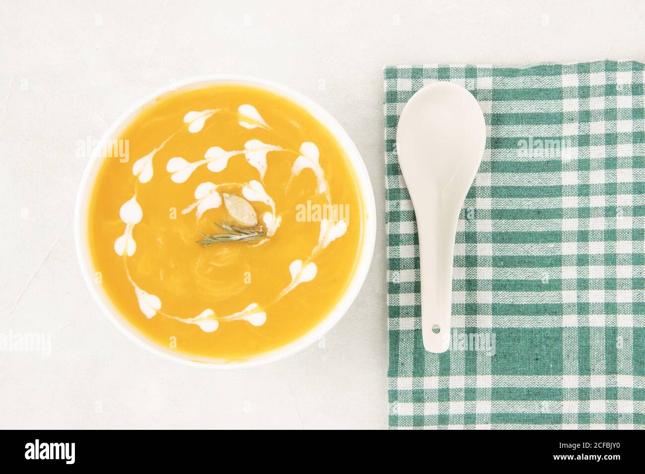 Kürbissuppe mit Rosmarinkraut, Sahne und Kürbiskernen in weißer Schüssel, Draufsicht, flach legen. Serviert und fertig zum Essen. Stockfoto