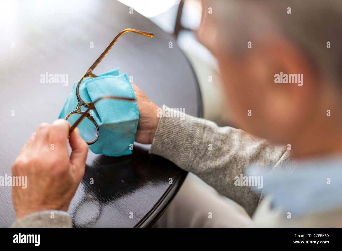 Älterer Mann, der Brillen mit Tuch abwischt Stockfoto