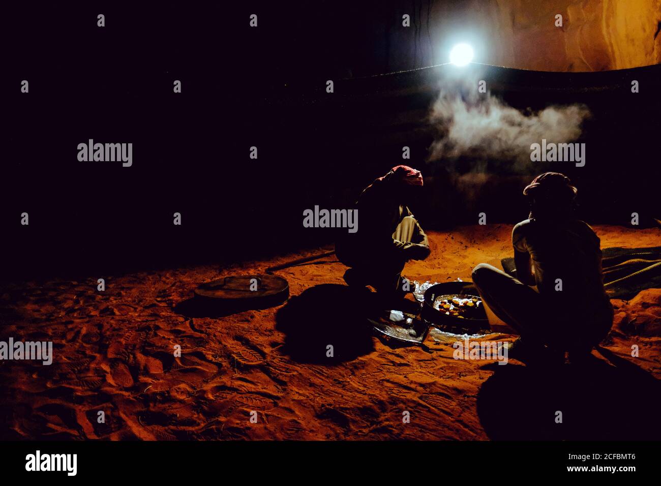 Zwei Beduinenmänner bereiten im Wadi Rum, Jordanien, ein traditionelles gekochtes Essen zu Stockfoto