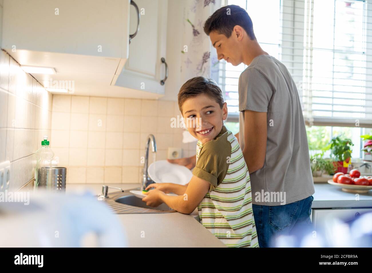 Zwei Jungen waschen das Geschirr im Spülbecken Stockfoto