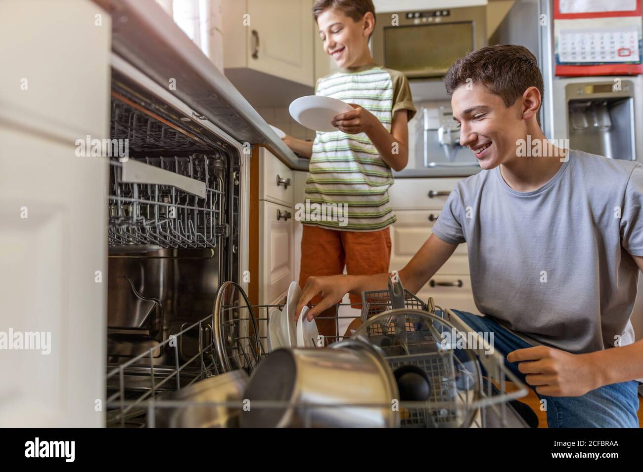 Zwei Jungen laden die Spülmaschine zusammen zu Hause Stockfoto