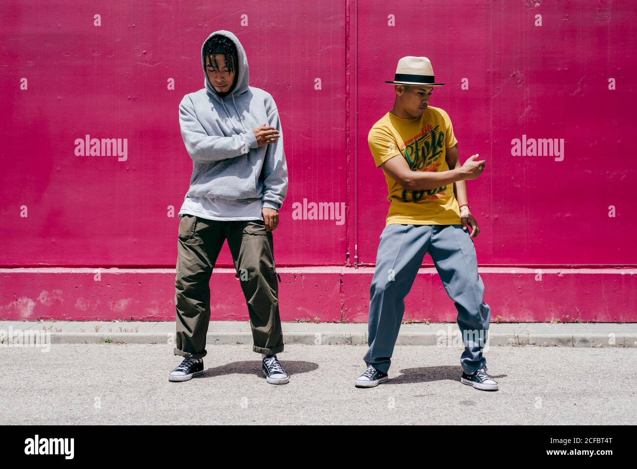 Zwei junge Männer tanzen neben einer rosa Wand Die Straße Stockfoto