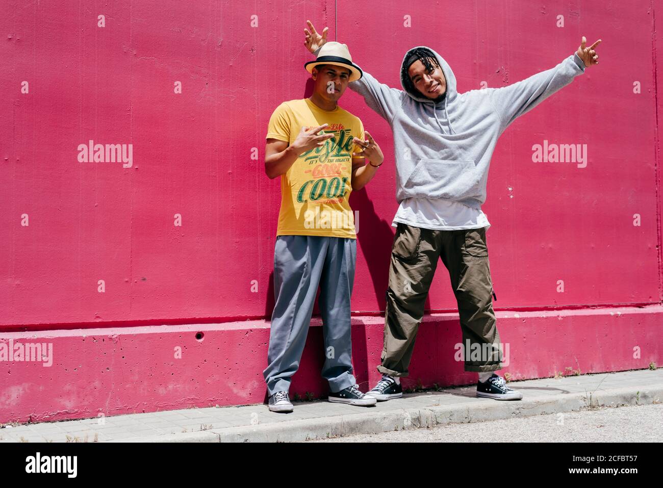 Zwei junge Stadttänzer stehen in der Nähe einer rosa Wand Auf der Straße Stockfoto