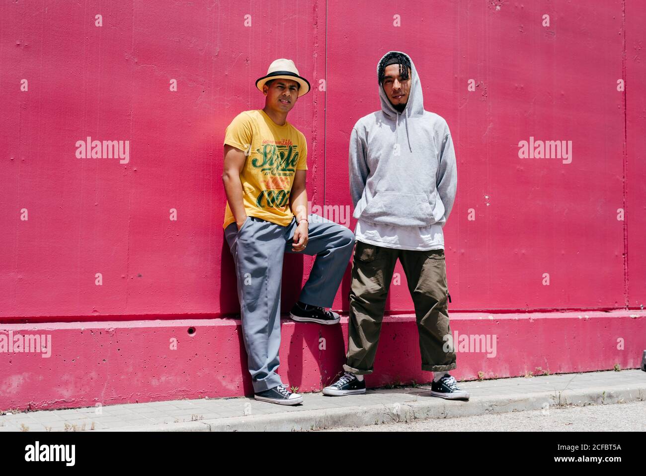 Zwei junge Stadttänzer stehen in der Nähe einer rosa Wand Auf der Straße Stockfoto