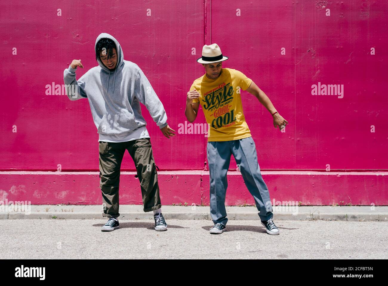 Zwei junge Männer tanzen neben einer rosa Wand Die Straße Stockfoto