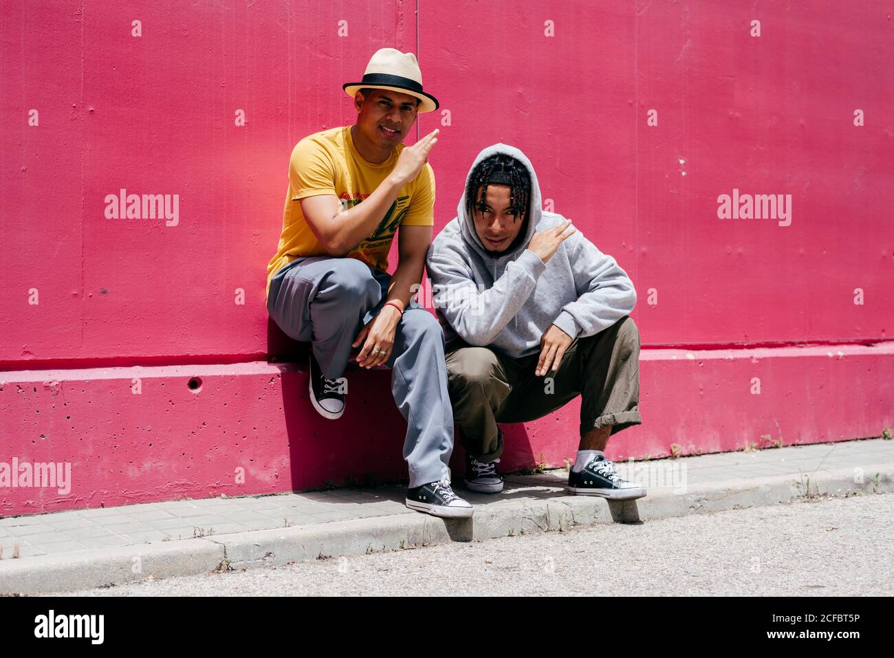 Zwei junge Stadttänzer stehen in der Nähe einer rosa Wand Auf der Straße Stockfoto
