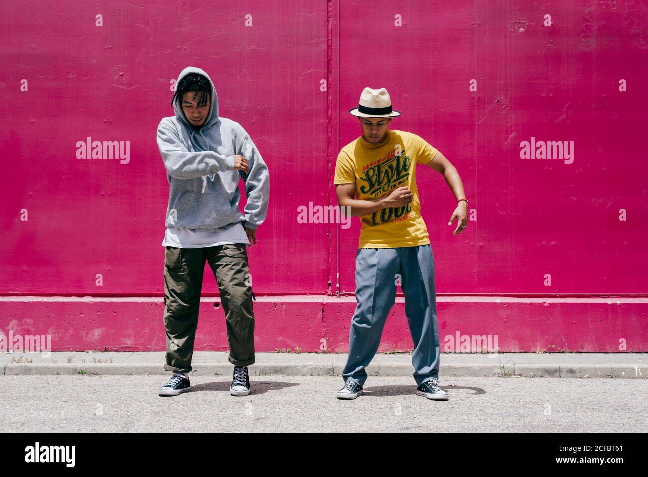 Zwei junge Männer tanzen neben einer rosa Wand Die Straße Stockfoto