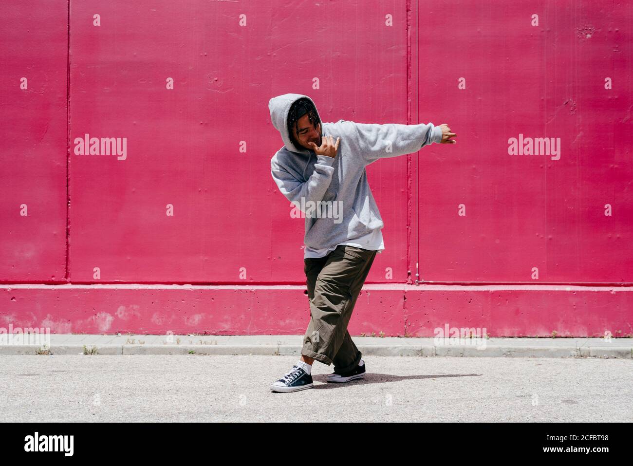 Junge hispanische Männer tanzen nahe einer rosa Wand Die Straße Stockfoto
