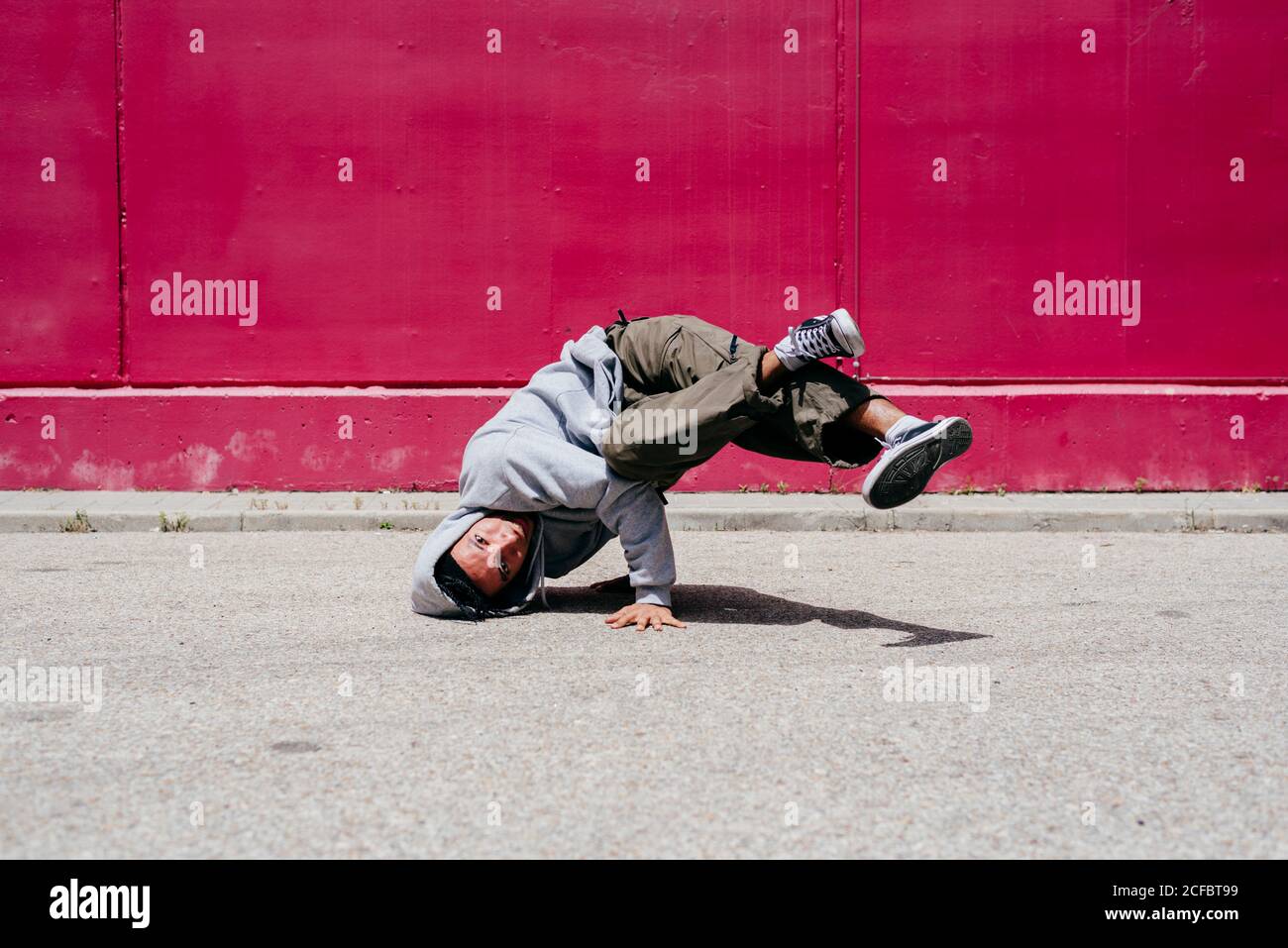 Junge hispanische Männer machen Akrobatik nahe einer rosa Wand Auf der Straße Stockfoto