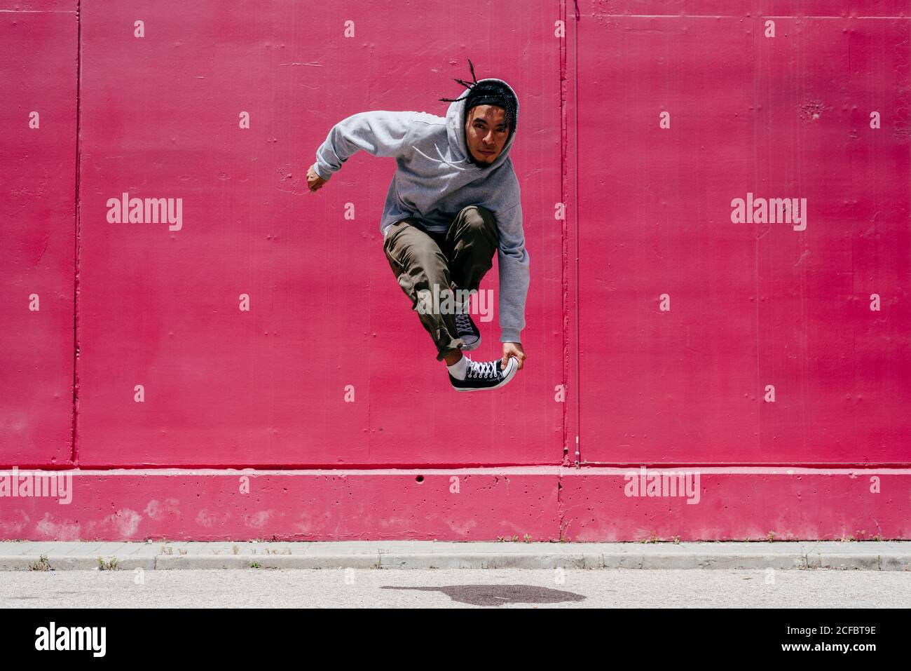 Junge hispanische Männer springen nahe an eine rosa Wand Die Straße Stockfoto