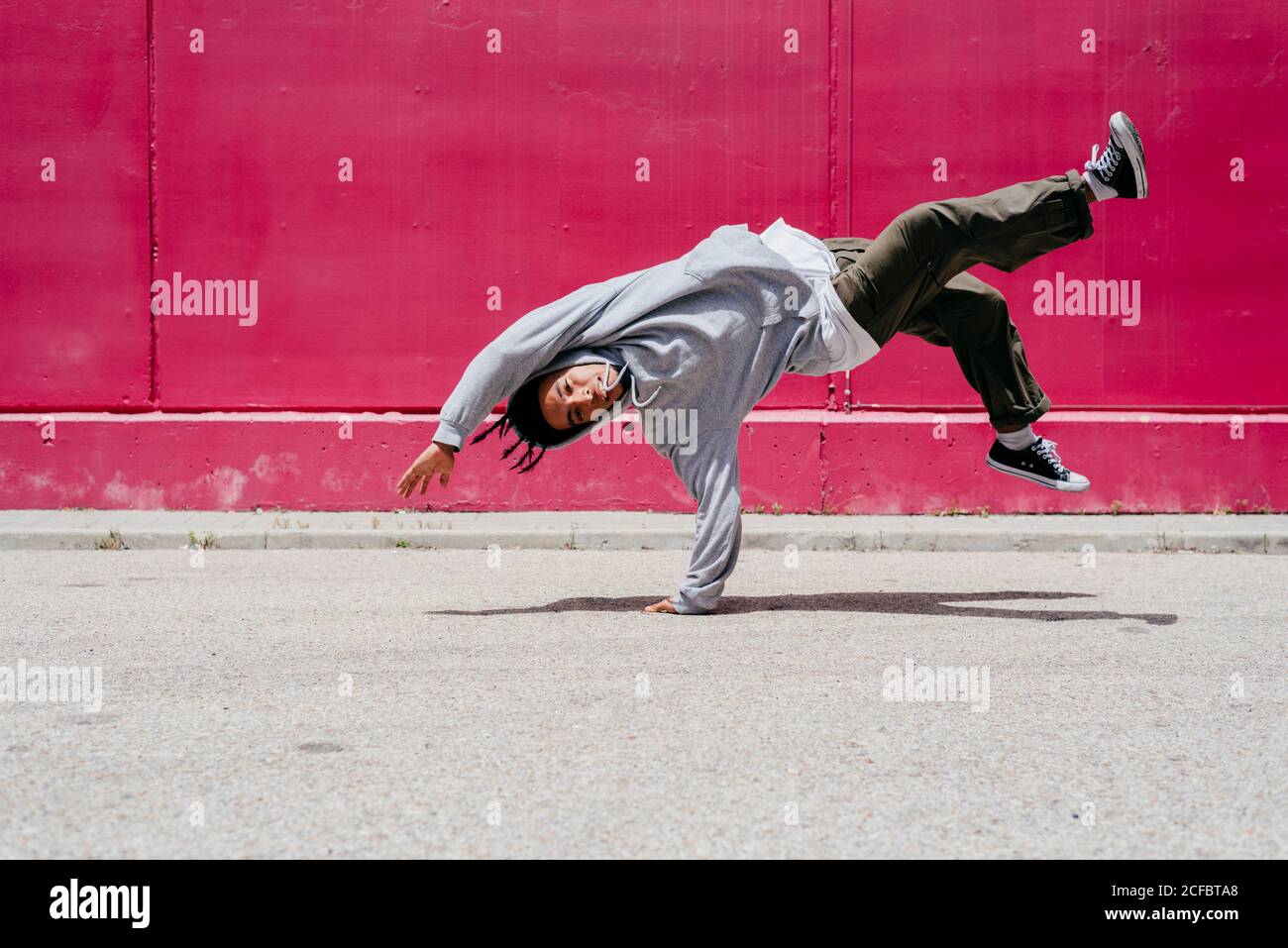 Junge hispanische Männer machen Akrobatik nahe einer rosa Wand Auf der Straße Stockfoto
