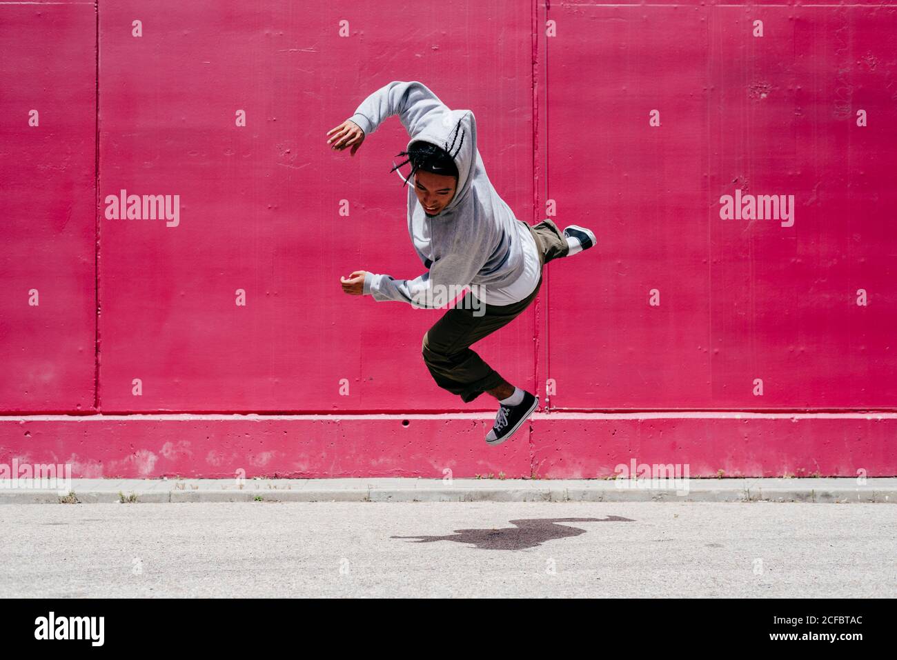 Junge hispanische Männer springen nahe an eine rosa Wand Die Straße Stockfoto