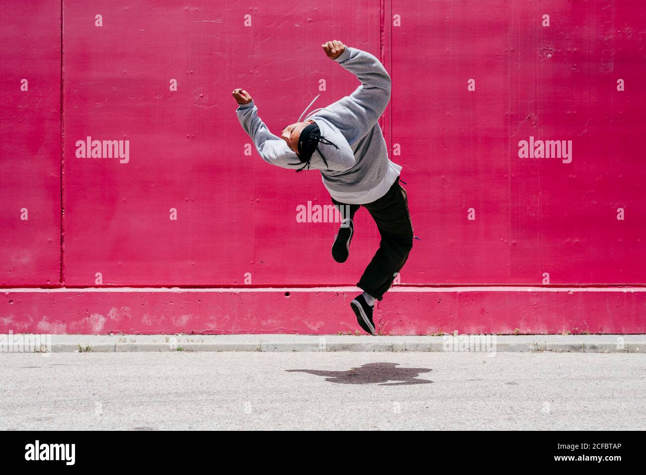 Junge hispanische Männer springen nahe an eine rosa Wand Die Straße Stockfoto