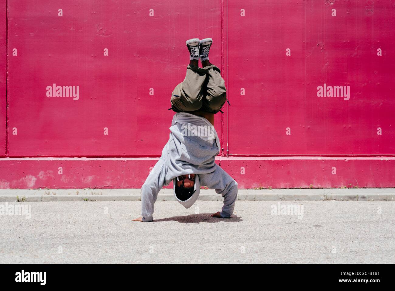 Junge hispanische Männer machen Akrobatik nahe einer rosa Wand Auf der Straße Stockfoto