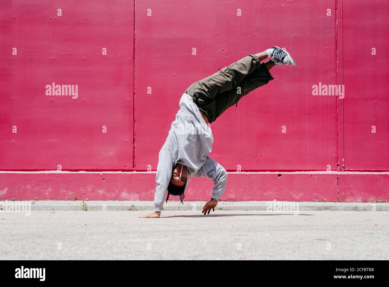 Junge hispanische Männer machen Akrobatik nahe einer rosa Wand Auf der Straße Stockfoto