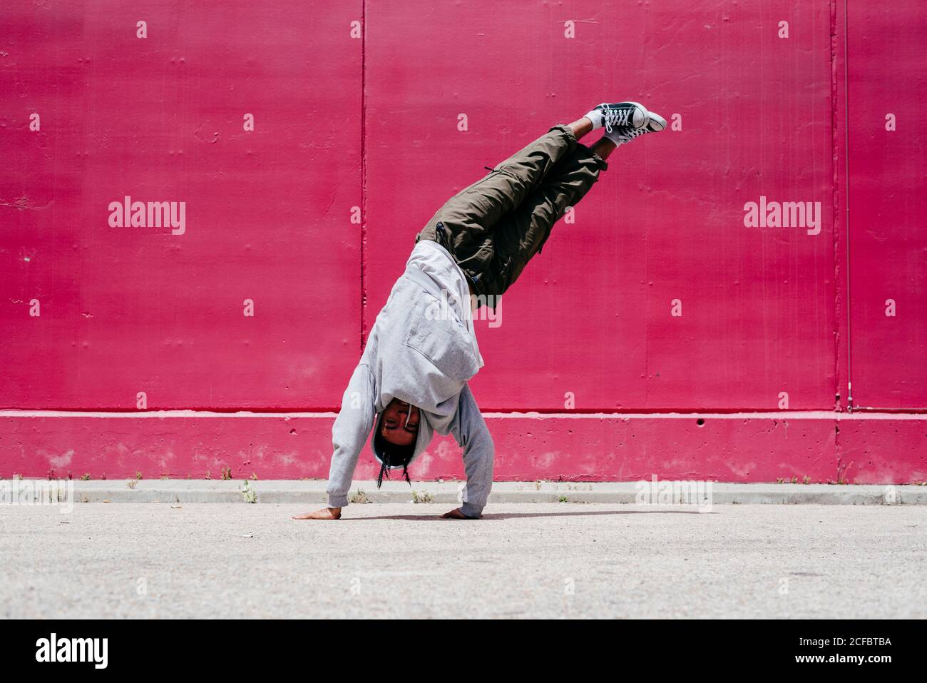 Junge hispanische Männer machen Akrobatik nahe einer rosa Wand Auf der Straße Stockfoto