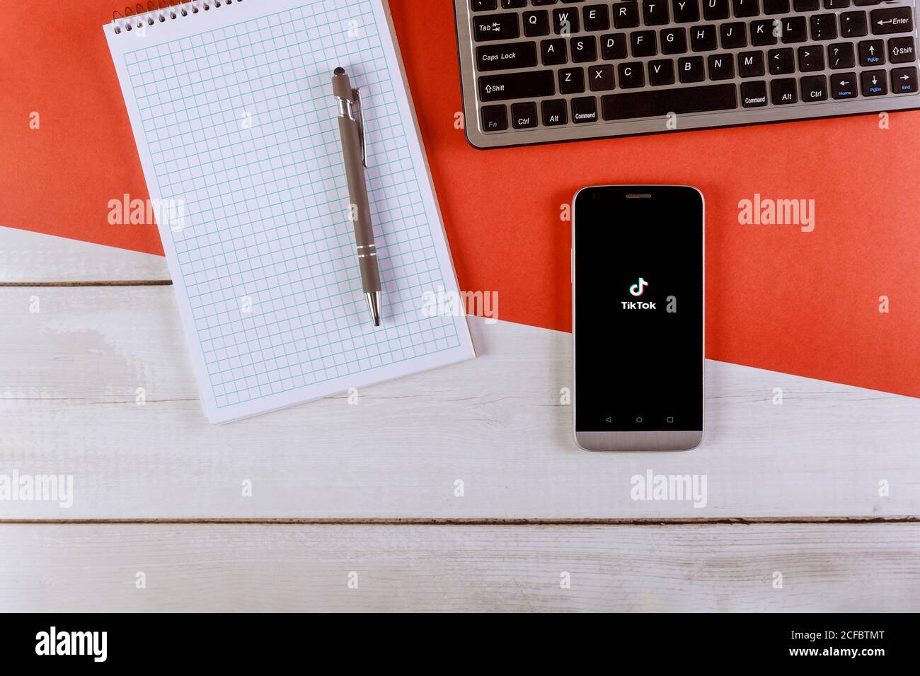 NEW YORK NY September 02 2020: TIK Tok Application Icon auf dem Smartphone-Bildschirm Arbeitsplatz mit Bürobedarf und Gadgets Smartphone mit Tastatur, Spiralnotizblock, Stift Stockfoto