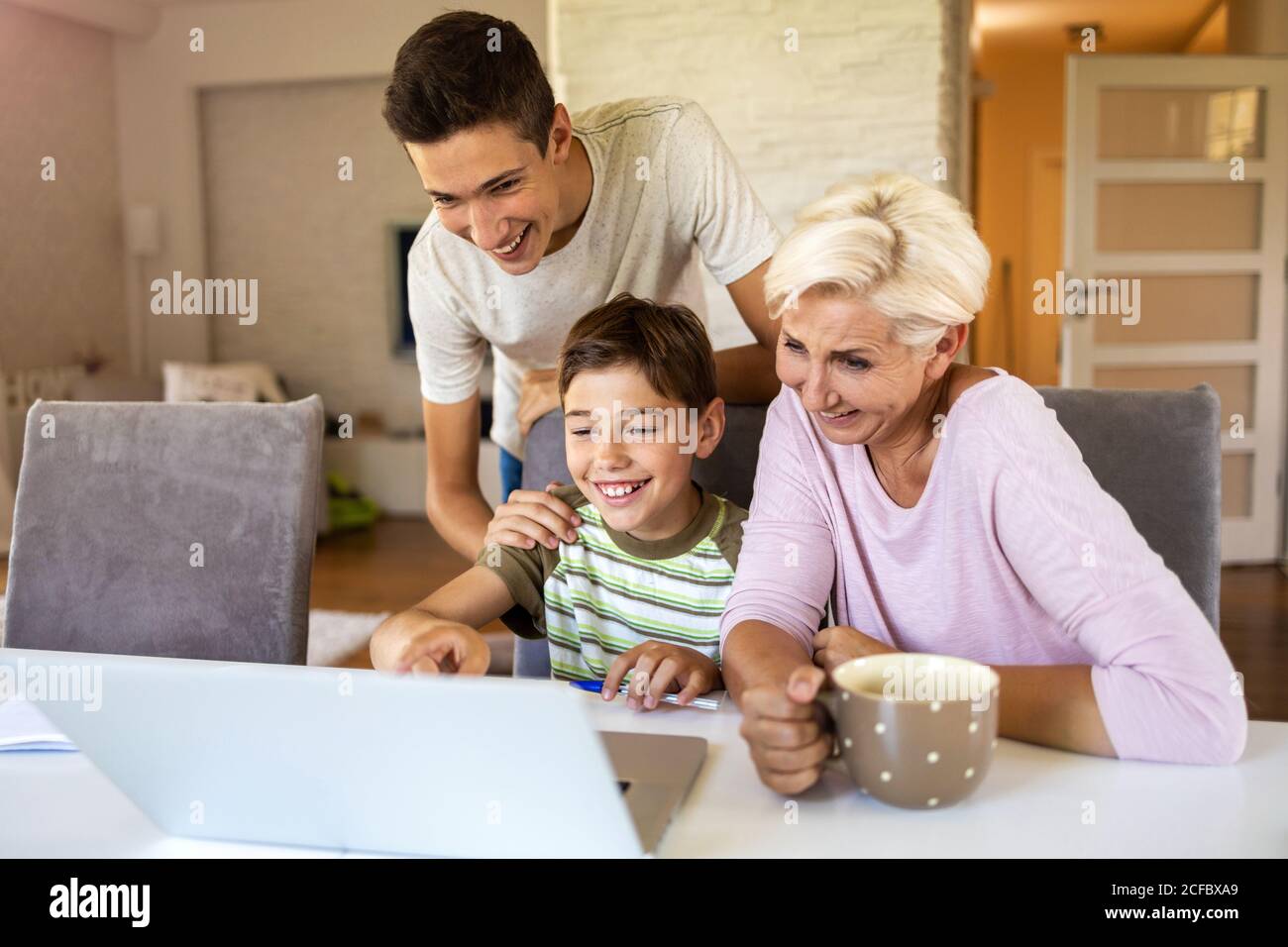Mutter mit ihren beiden Söhnen mit Laptop zu Hause Stockfoto