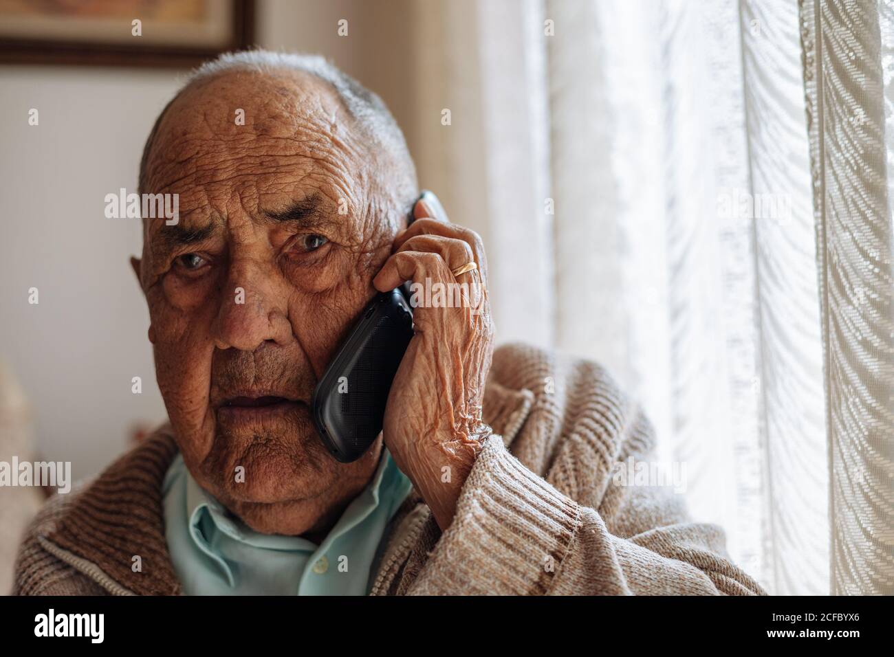Älterer Mann ruft von seinem Telefon in seinem Haus Stockfoto