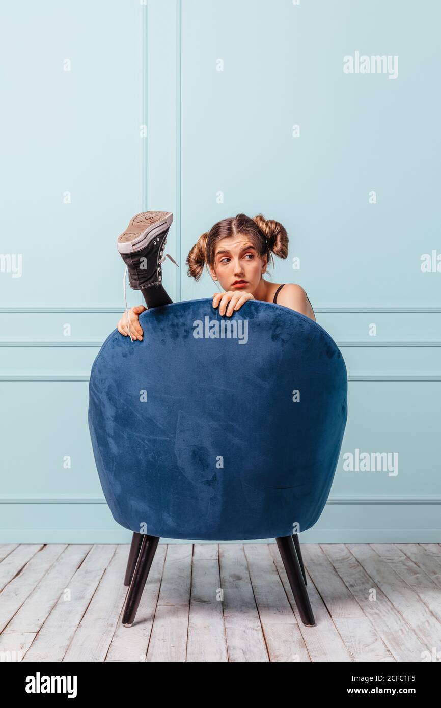 Teen Mädchen versteckt und glücklich in einem blauen Sessel auf Türkisfarbener Hintergrund Stockfoto