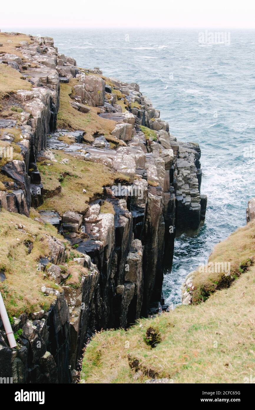 Meereswellen in Schottland auf grünen Klippen Stockfoto