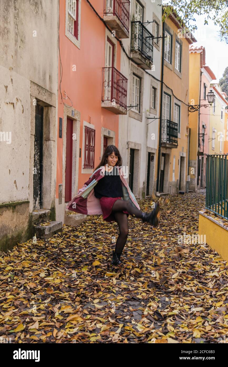 Freudig aktive junge Frau, die beim Spaziergang in der Straße von Lissabon hereinkickt Stockfoto