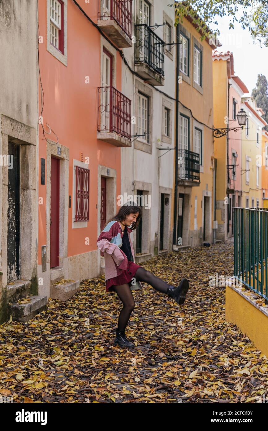 Freudig aktive junge Frau, die beim Spaziergang in der Straße von Lissabon hereinkickt Stockfoto