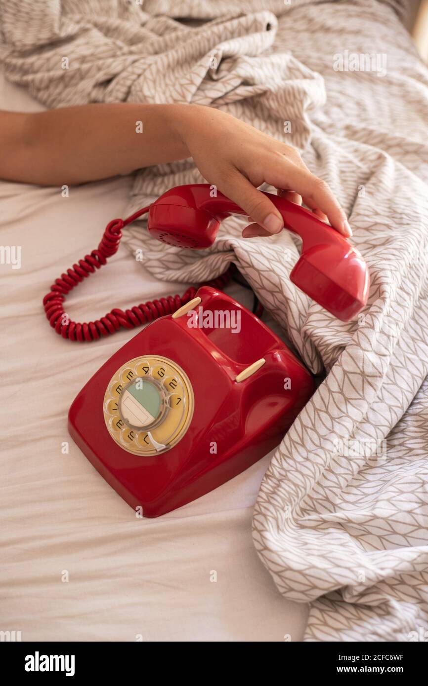 Von oben unkenntlich Dame Hände setzen roten Hörer auf Retro Telefon nach dem Gespräch auf dem Bett Stockfoto