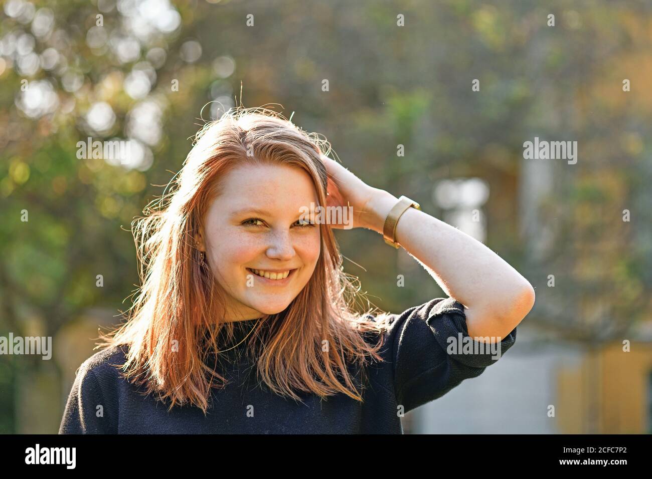 Junges Mädchen mit rötlichen Haaren und Sommersprossen steht im Freien und Lächelt auf das Kameraportrait Stockfoto