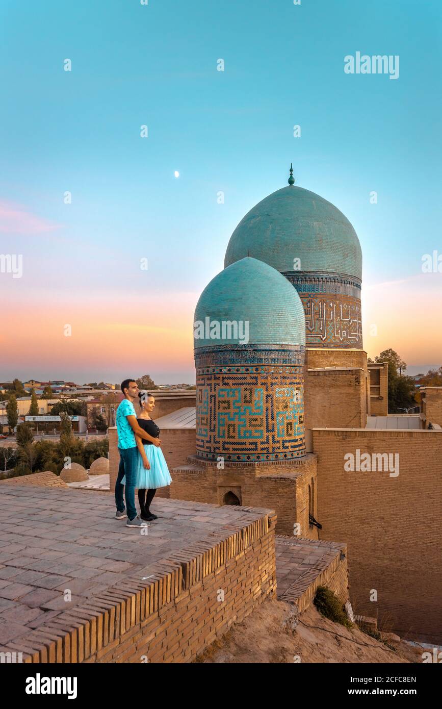 Paar umarmen einander in der Nähe von alten islamischen Gebäude mit Kuppeln während des Besuchs Shah-i-Zinda in Samarkand, Usbekistan Stockfoto