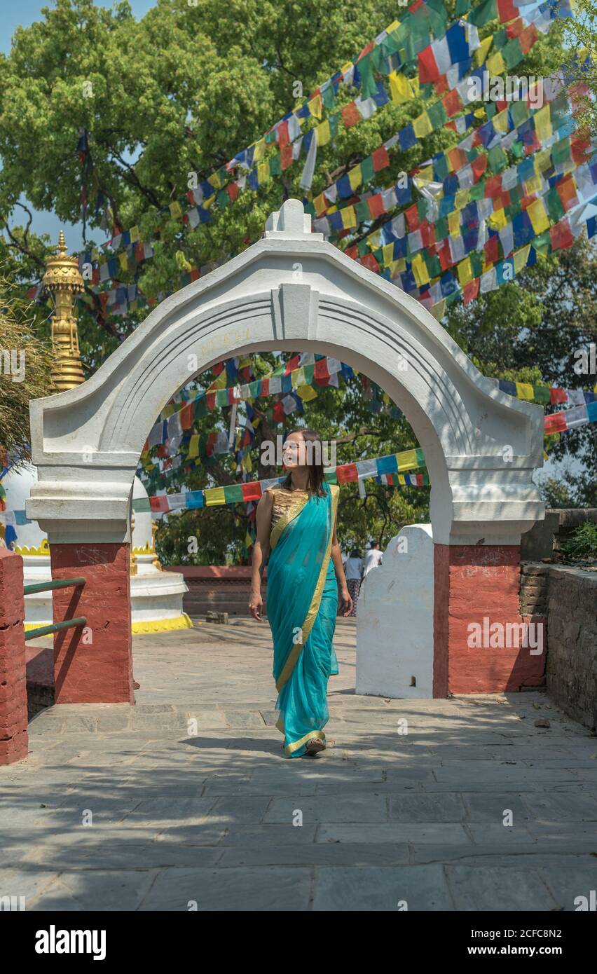 Weibliche Tourist in Kleid wegschauen, während sie auf dem Bürgersteig stehen Spaziergang auf alten buddhistischen Tempel unter bunten Girlande mit Fahnen An sonnigen Tag Stockfoto