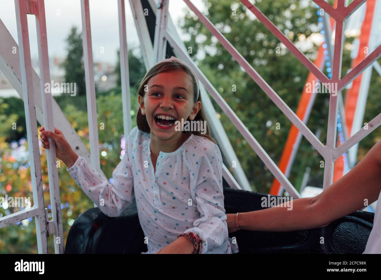 Aufgeregt kleines Mädchen lachen beim Reiten Riesenrad mit Ernte Mutter auf verschwommenem Hintergrund von Herbstbäumen im Vergnügungspark Stockfoto