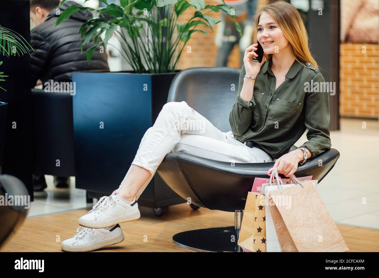 Frau beim Einkaufen und Sitzen, während sie auf ihrem Handy spricht Stockfoto