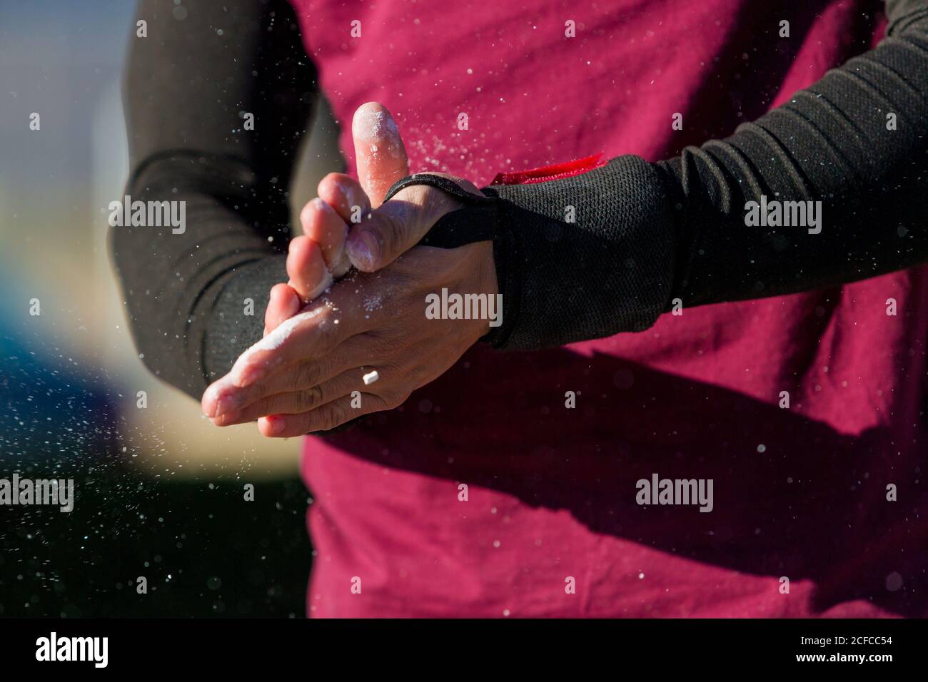 Nicht erkennbarer männlicher Athlet in Sportkleidung, die Hände mit Puder bedeckt reiben Während des Trainings an sonnigen Tagen Stockfoto