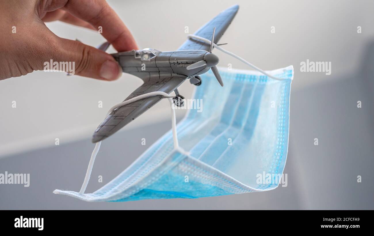 Eine Gesichtsmaske wie ein Fallschirm auf einem kleinen platziert Spielzeug Plastikflugzeug Stockfoto