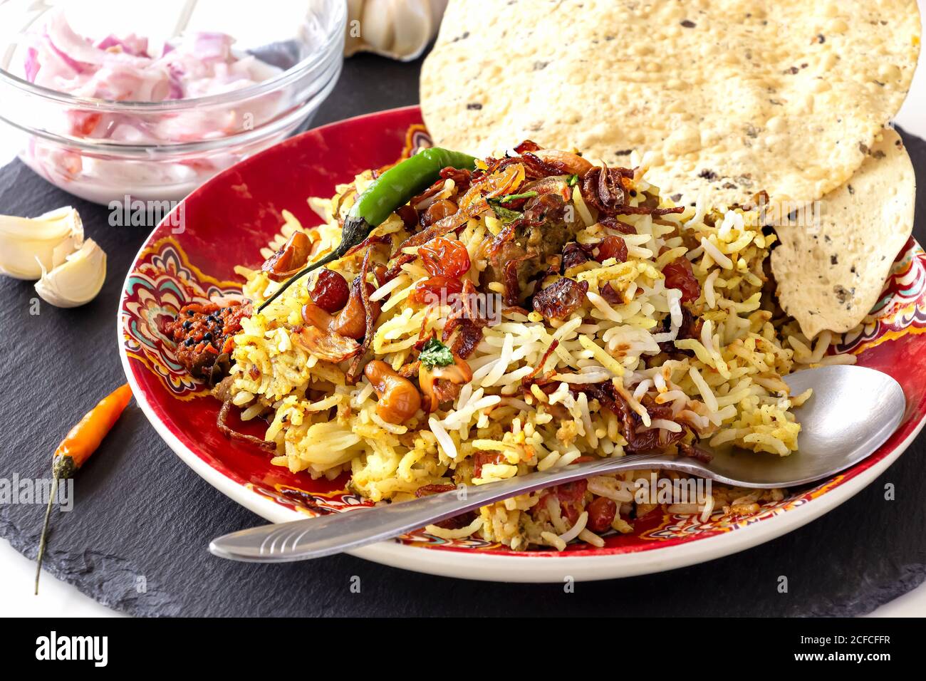 Halal Indian Chicken oder Hammel Biryani serviert mit Joghurt Tomate Raita auf weißem Hintergrund. Selektiver Fokus. Stockfoto