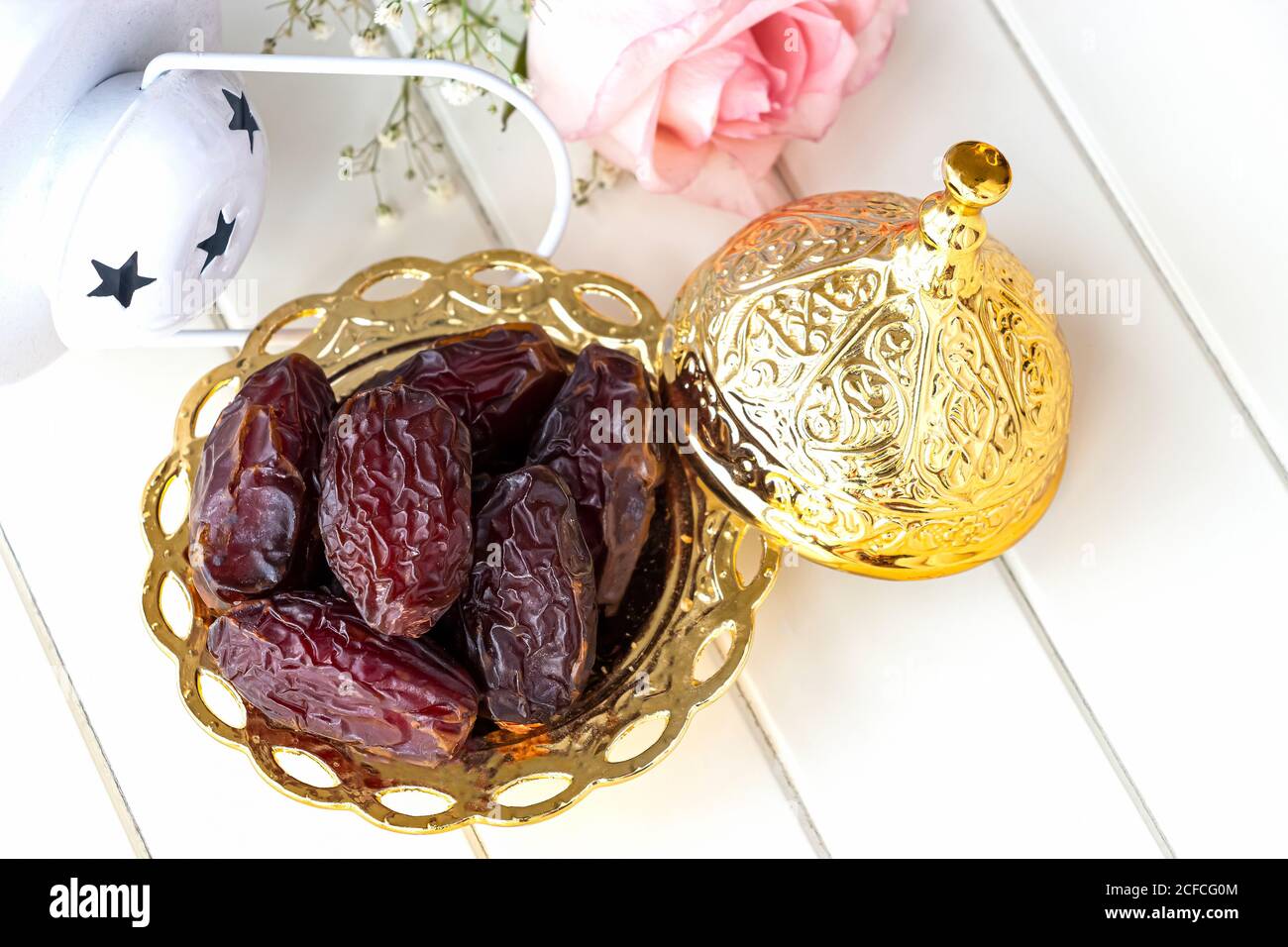Bio getrocknete Datteln in traditionellen arabischen goldenen Teller und rosa Rose. Konzept des Heiligen Monats Ramadan. Draufsicht. Stockfoto