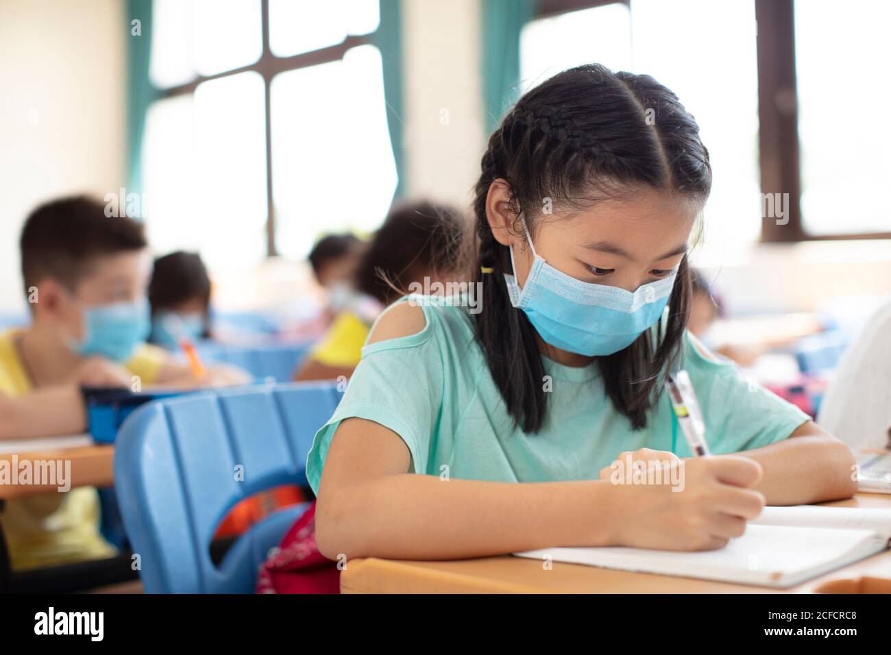 Schüler tragen Maske und studieren im Klassenzimmer. Stockfoto