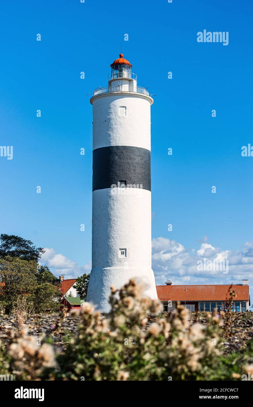 Leuchtturm, weiß mit einem schwarzen Streifen gegen einen blauen Himmel. Stockfoto