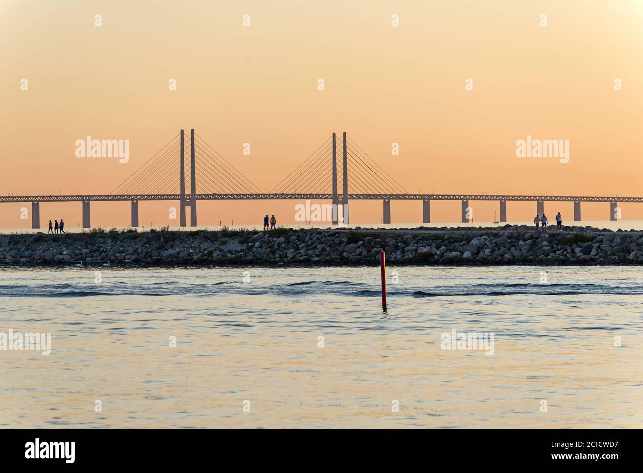 Seitenansicht der Øresund-Brücke im Abendlicht, Spaziergänger auf der Pier im Vordergrund Stockfoto