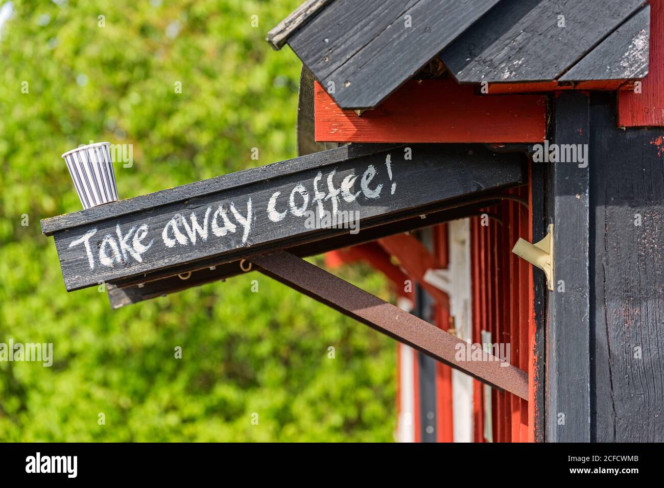 Kaffeetasse steht auf Baldachin mit Take Away Kaffee Schriftzug, Holzhaus im Tor Stockfoto