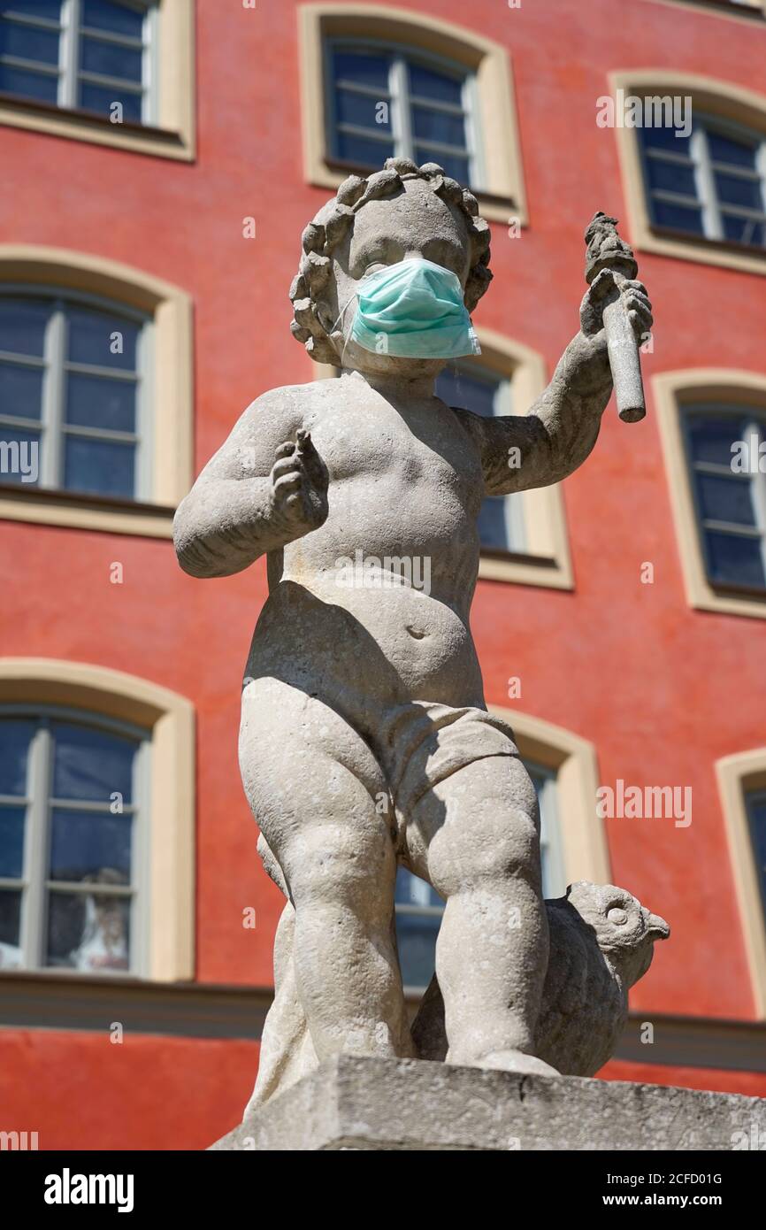Deutschland, Bayern, Oberbayern, Mühldorf am Inn, Stadtplatzbrunnen, Brunnenbuberl, Brunnenfigur mit Schutzmaske, Virenschutz Stockfoto