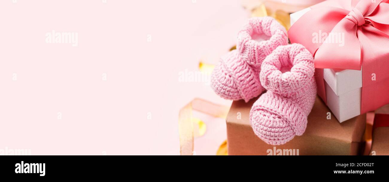 Schöne Komposition mit rosa Baby Booties und Geschenkbox auf rosa Hintergrund. Konzept der Baby-Dusche-Party, erste Geburtstag Urlaubskarte, Kopierer Platz, b Stockfoto