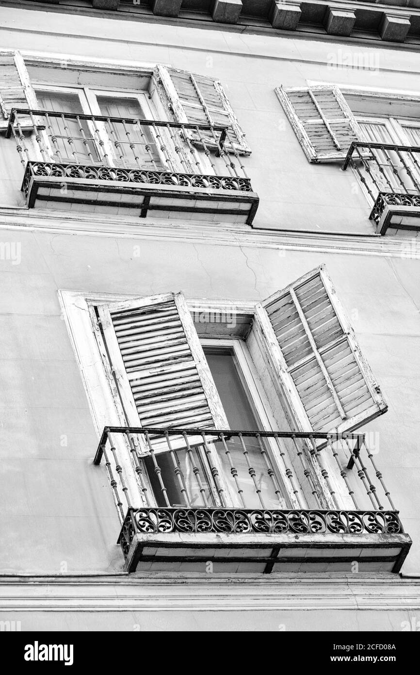 Ein weißes Gebäude mit weißen Fensterläden und schwarzen schmiedeeisernen Balkonen; Madrid, Spanien. Stockfoto
