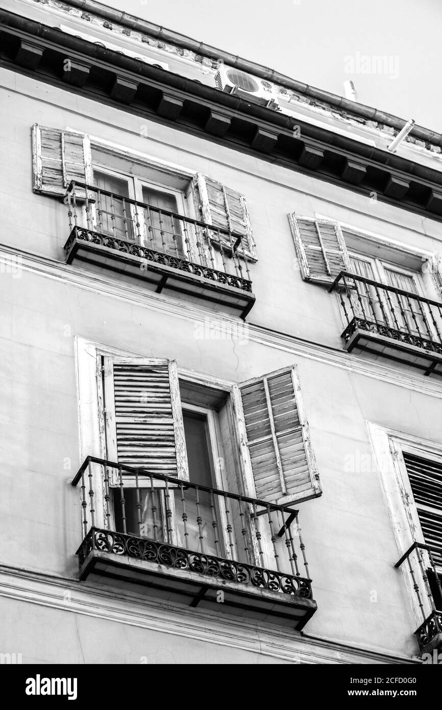 Ein Schwarz-Weiß-Foto von der Vorderseite eines Gebäudes, mit hölzernen Fensterläden und Balkonen in allen Fenstern; Madrid, Spanien. Stockfoto